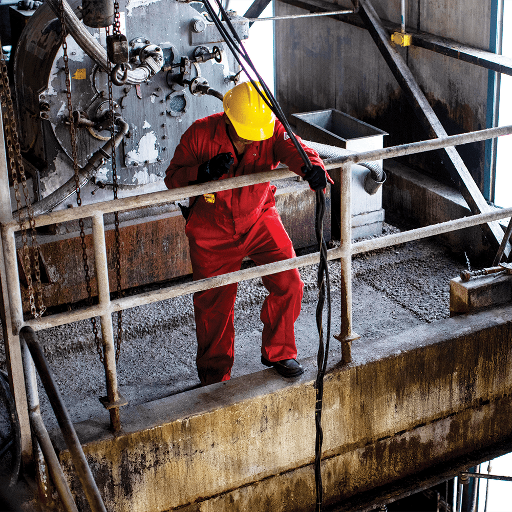 power plant employee looks down from a balcony in the plant next to heavy machinery