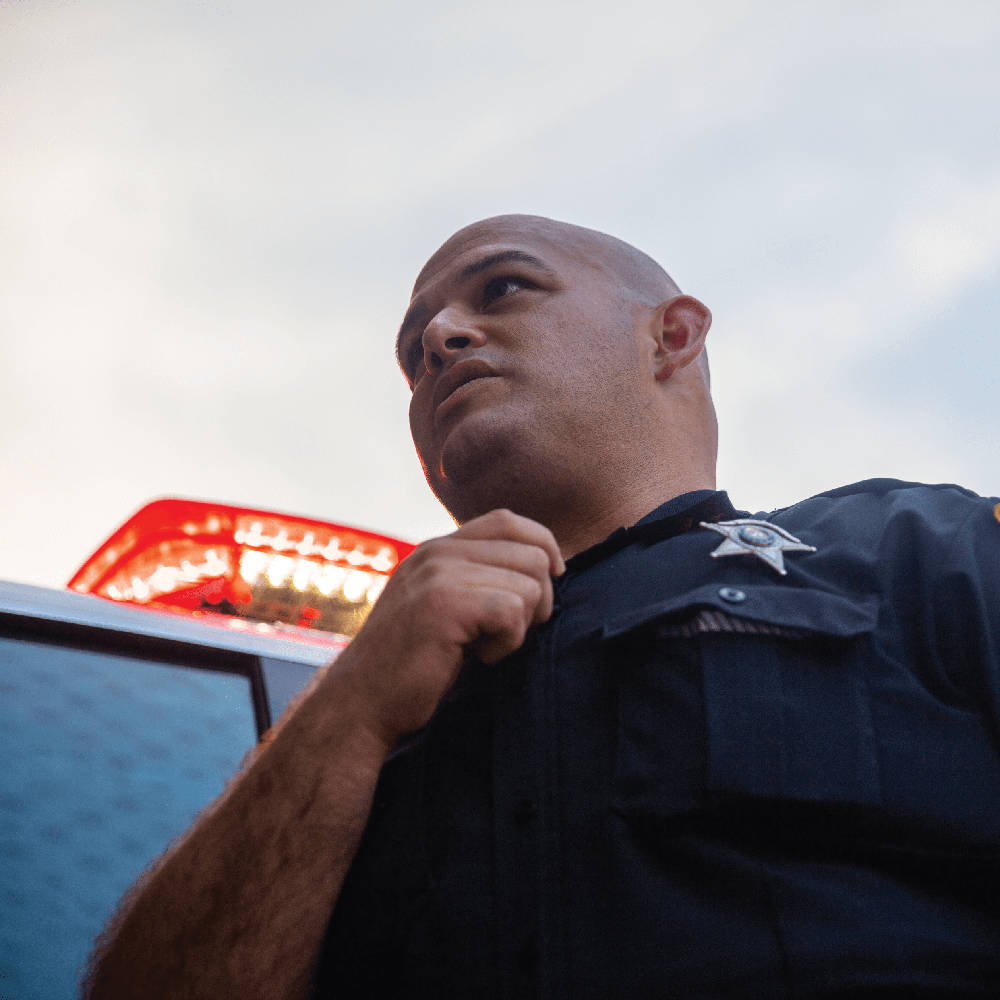 police officer looks up while standing next to police vehicle