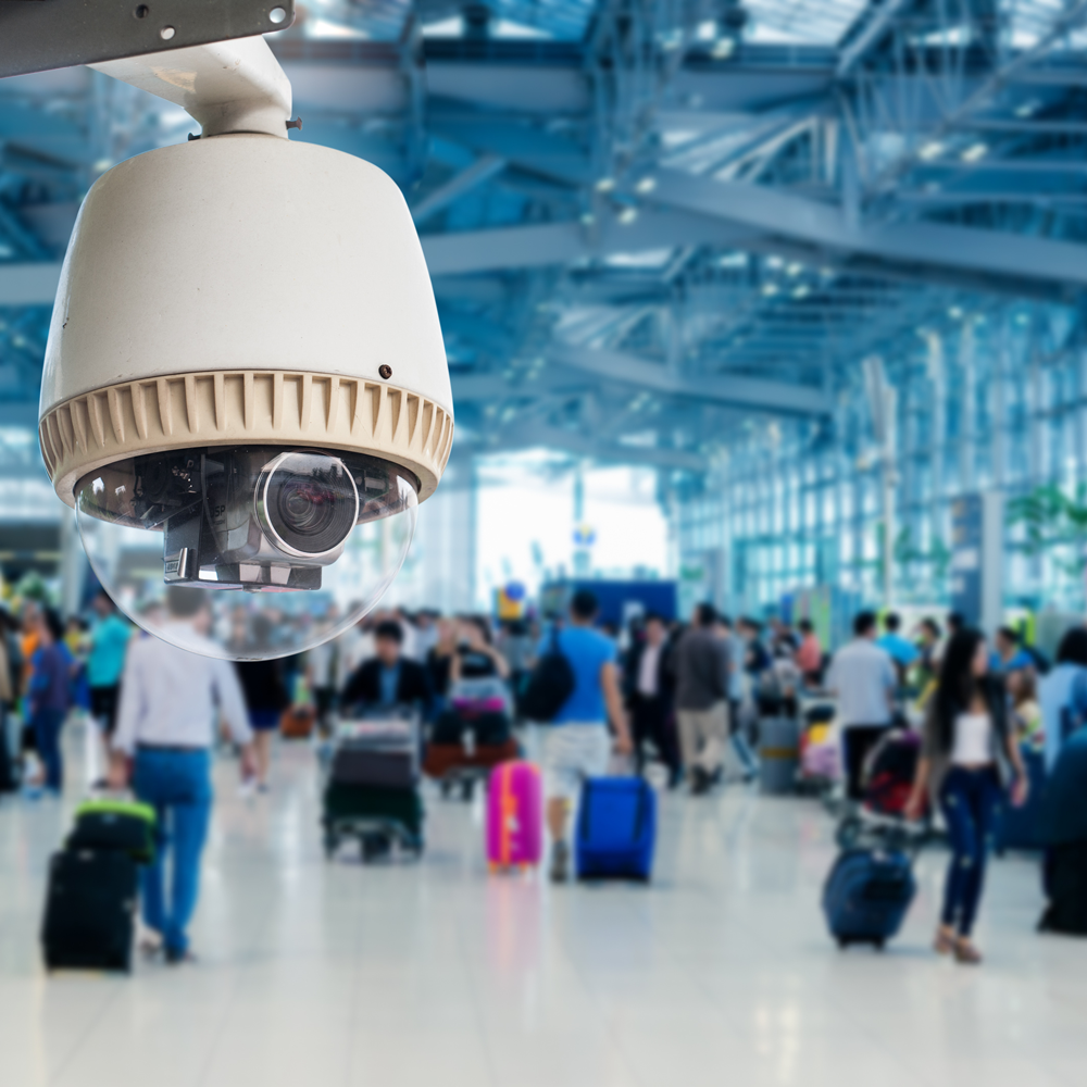a busy airport terminal with a video surveillance camera installed above