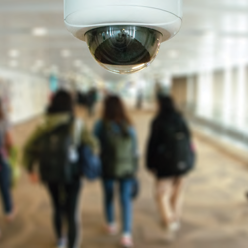 classmates walk in school hallway with video surveillance cameras installed in the ceilings above them